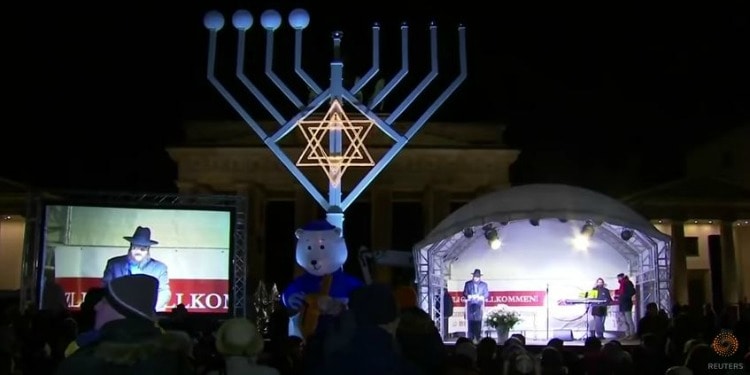 A large menorah statue in Berlin in front of a large crowd.