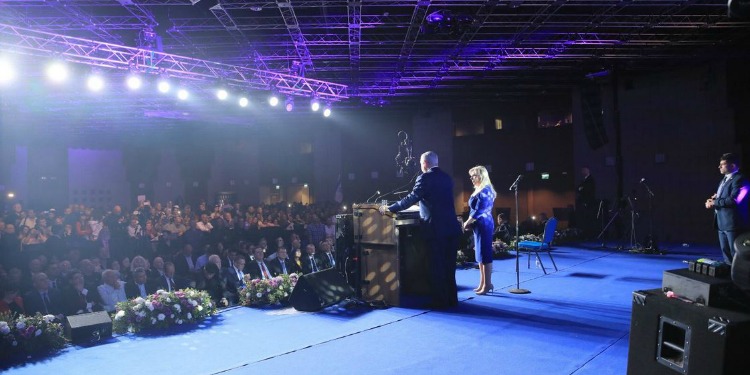 Bibi and wife on stage during an event.