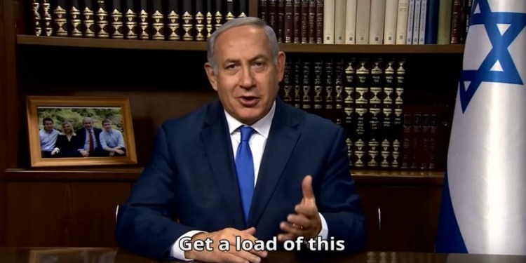 Bibi sitting in a library with books and the Israeli flag behind him.