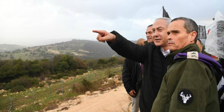 Bibi standing with several other men on a mountain pointing into the distance.
