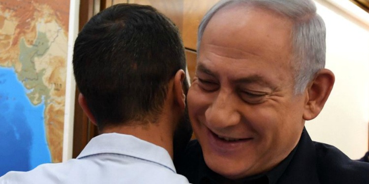 Bibi hugging a young man and smiling.