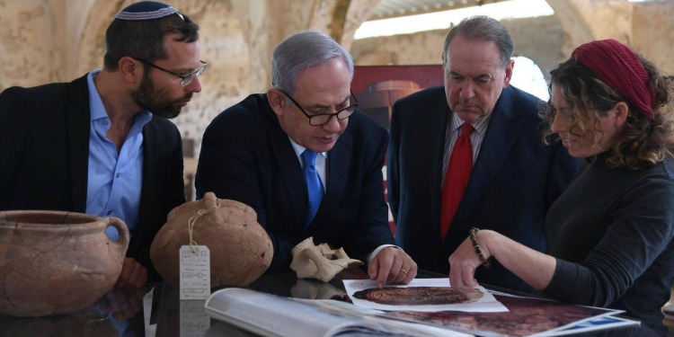 Bibi, Mike Huckabee and two other people going over artifacts and documents.