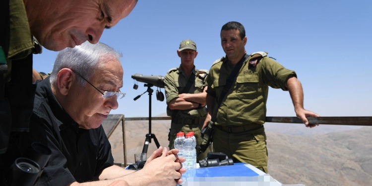 Bibi sitting with three soldiers outside on a balcony while overlooking paperwork.
