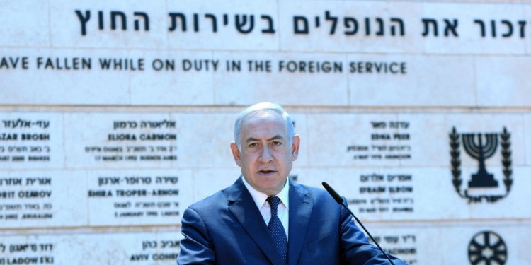 Bibi giving a speech in front of a memorial.