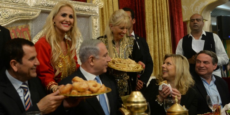 Bibi, his wife, and others gathered in a gold room with food and drink around them.