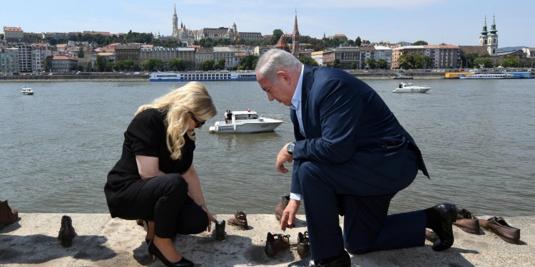 Bibi and his wife kneeled around shoes on the Danube bank.