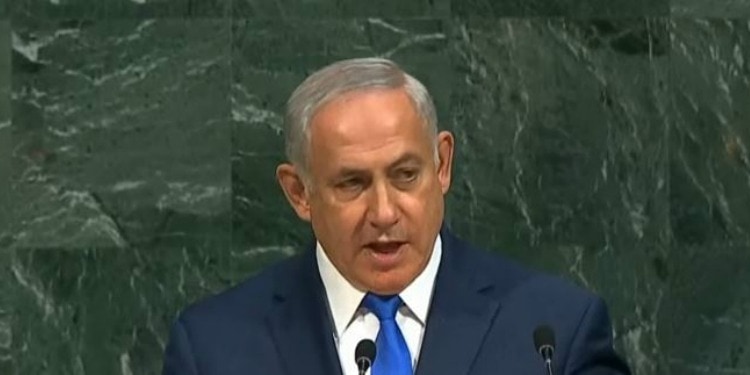 Bibi giving a speech at the UN podium with a green background behind him.