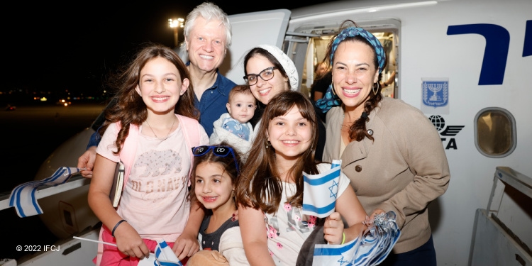 Yael Eckstein and Bishop Lainer standing with a family who just made Aliyah.
