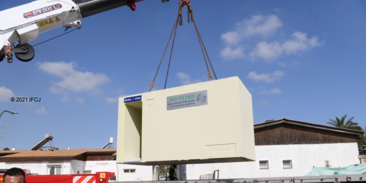 A crane placing an IFCJ branded bomb shelter in place.