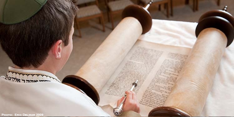 Young boy reading through the torah.