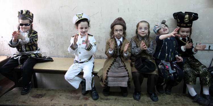 Six young boys seating on a bench, all dressed up for Purim.