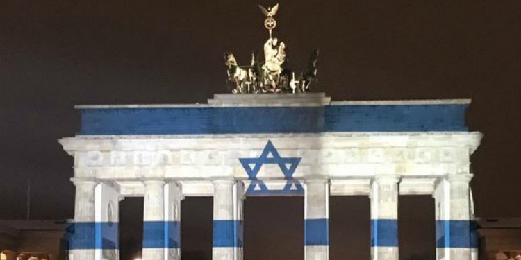 A gate with the Israeli flag projected on it and a gold topper.