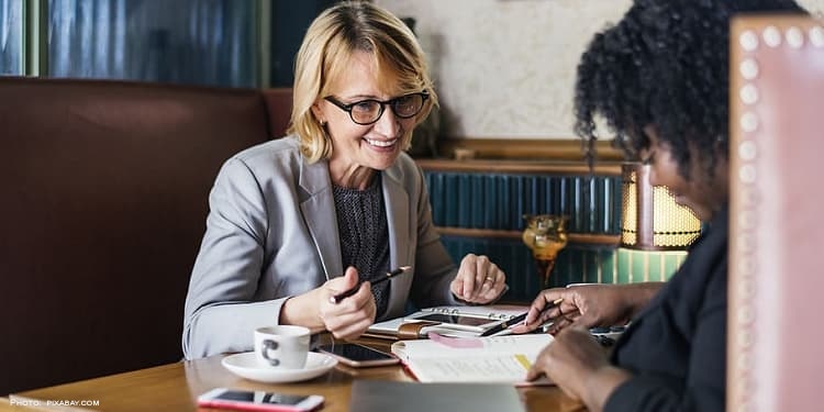 Two business women speaking over coffee.