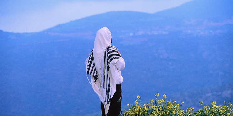 Person in a white robe looking at a mountain.