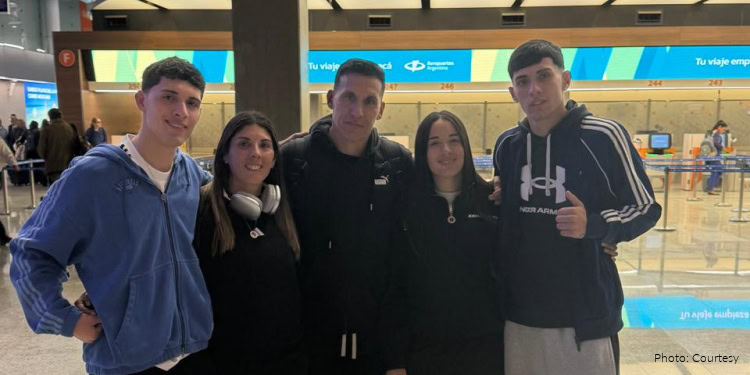 The Caballero Family, new olim from Argentina, at Ezeiza International Airport. group photo of family standing together in airport, smiling, happy, adult man, adult woman, two young adult men, and one young adult woman, blue and black sweatsuits, thumbs up