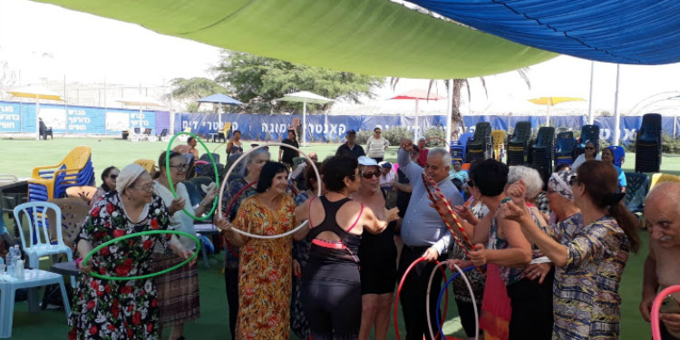 Several ladies gathered together hula hooping.