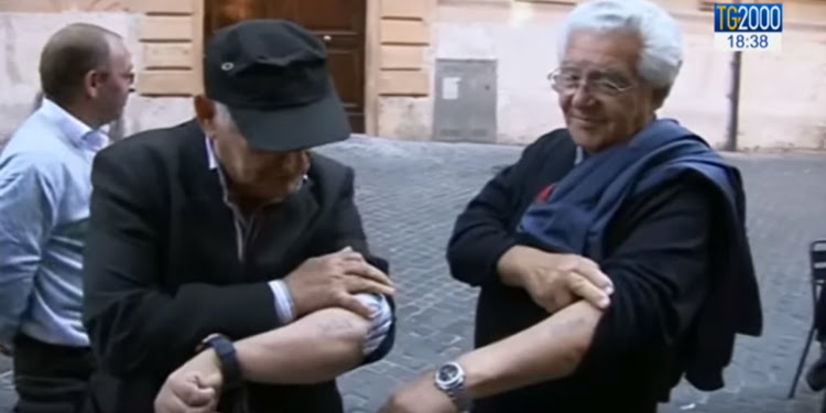 Two men showing their arm tattoos to one another.