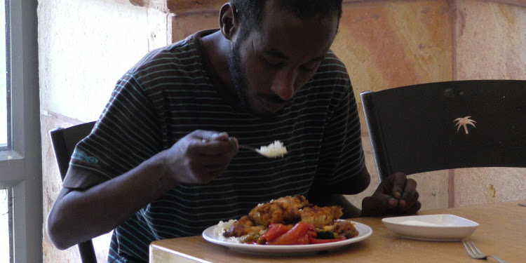 A man eating a meal at Carmei Ha'ir Soup Kitchen