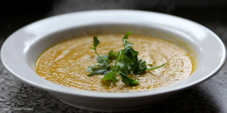 Close-up of Tosfet, a traditional Middle Eastern side dish, served in a white bowl garnished with fresh herbs, on a dark surface.