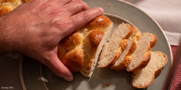 Person cutting Challah on Shabbat