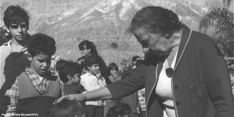 Black and white image of an elderly woman touching a boy's head.