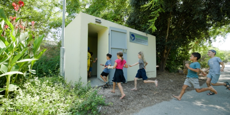 Children running into bomb shelter in park.