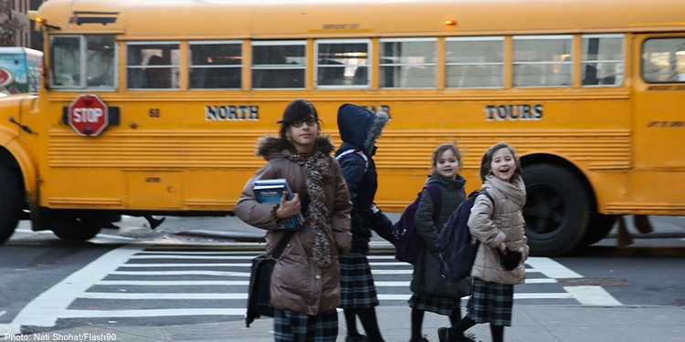 Children crossing the crosswalk along side of a school bus