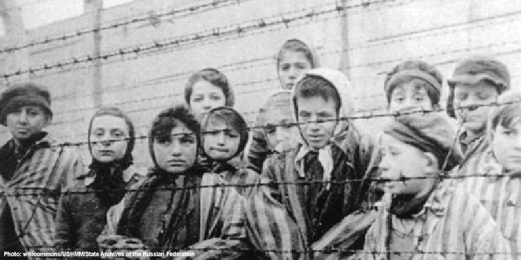 Black and white image of children behind a fence during the Holocaust.