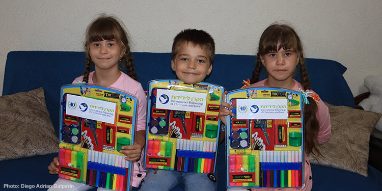 Children sitting on a couch holding colored marker kits