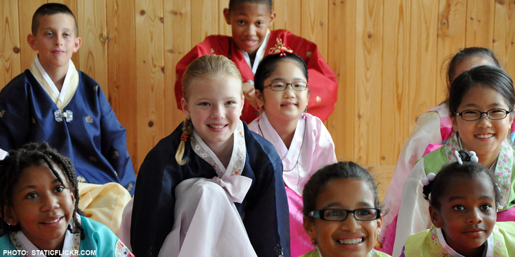 Nine children of different ethnicities in different robes smiling at the camera.