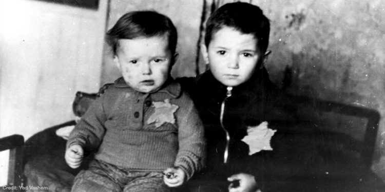 Black and white image of two young boys sitting on a chair.