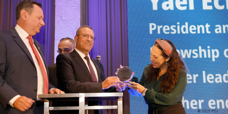 Israel President receiving an award at IFCJ event, with officials and a woman presenting the plaque, symbolizing leadership and support for Jewish communities.