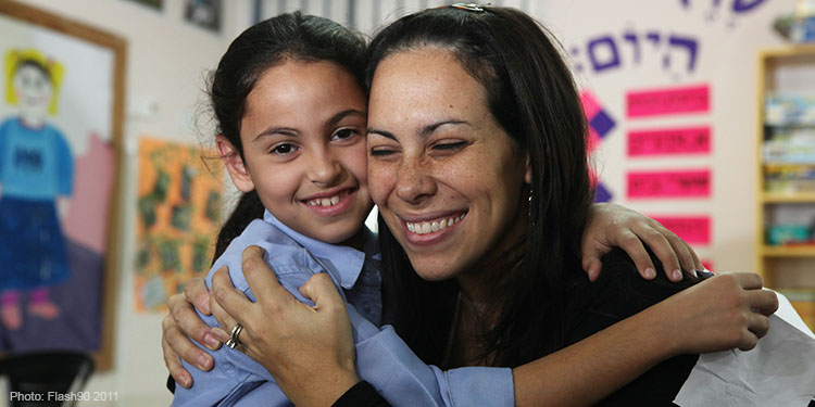 Yael Eckstein hugging a young girl and smiling.