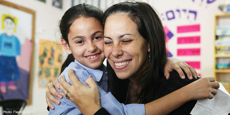 Yael Eckstein hugging a young girl and smiling.