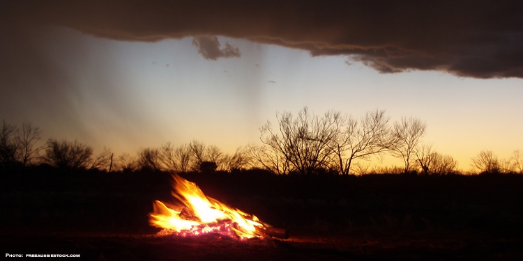 Fire in the middle of wilderness while the sun is setting behind it.