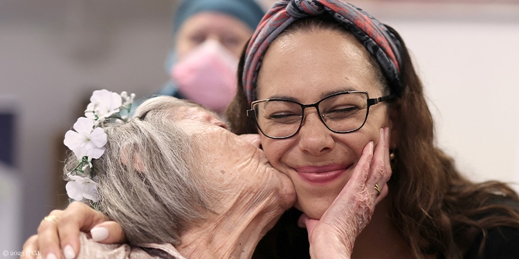 Yael being kissed by an elderly woman at her 100th birthday celebration