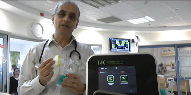 Man standing with an incubator in his hand while a CoughSync camera is facing the camera.