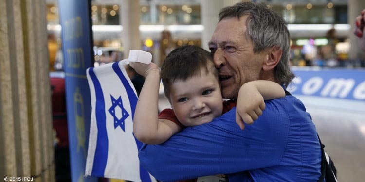 Little boy hugging his father while holding an Israeli flag.