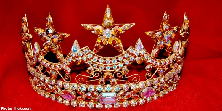 A bejeweled crown in front of a red background.