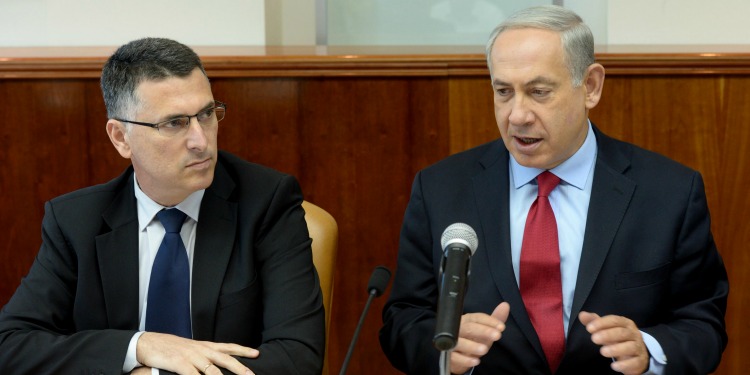 Bibi talking in front of a mic next to another man in a suit.