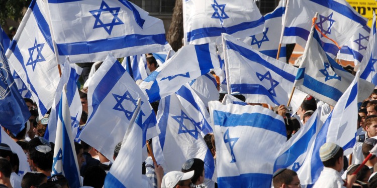 Crowd of people waving Israeli flags.