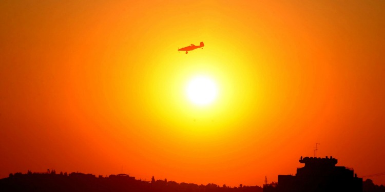 A helicopter flying over the sunset of a city.