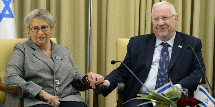 Israeli First Lady sitting with husband as they smile out into the crowd.