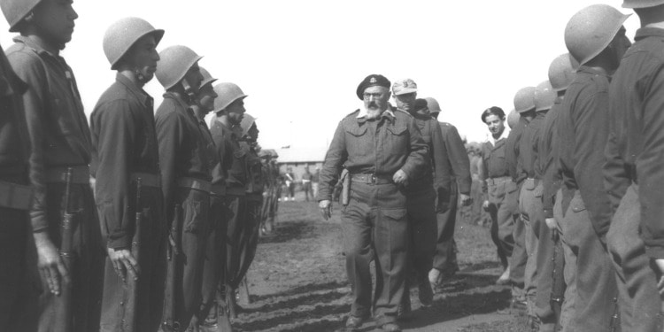 Dated image of a man walking through rows of soldiers.