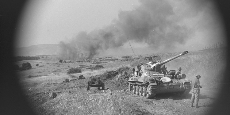 Black and white image of a tank and soldiers in it on war grounds.