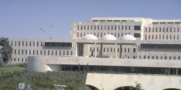 A large concrete building with a light blue sky above it.