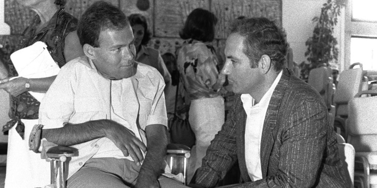 Black and white image of two men sitting down and talking to each other.