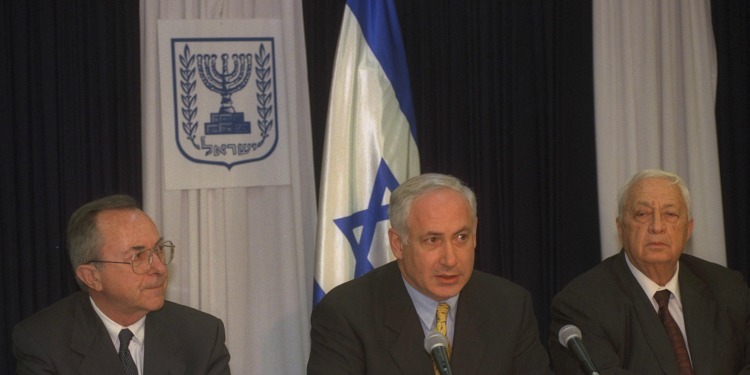 Three men sitting together in front of a podium.