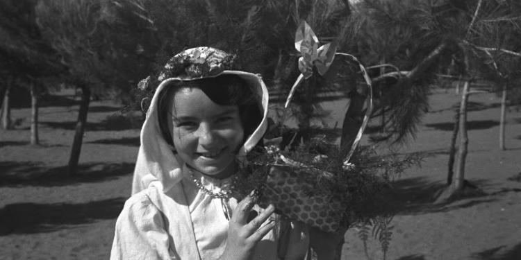 Black and white image of a girl holding a small basket in a field.