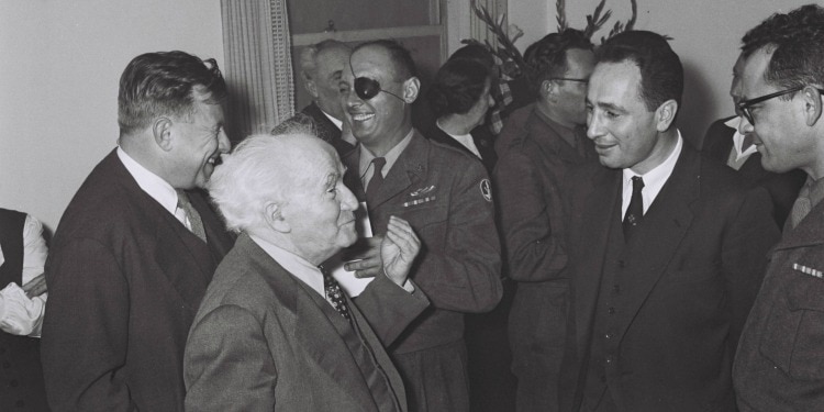 Several older men in suits and uniforms smiling and talking together.